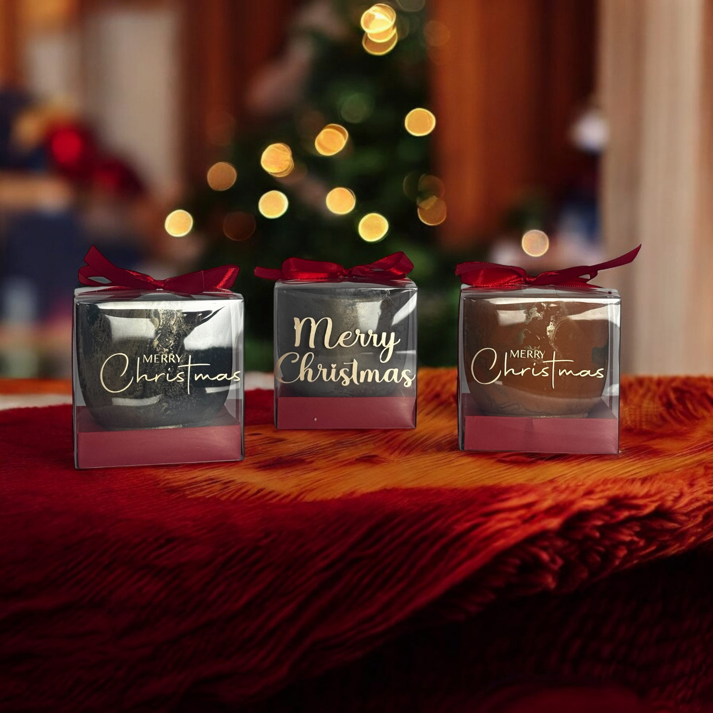 'Merry Christmas' gift boxes on a red surface with a blurred Christmas tree in the background. Candle