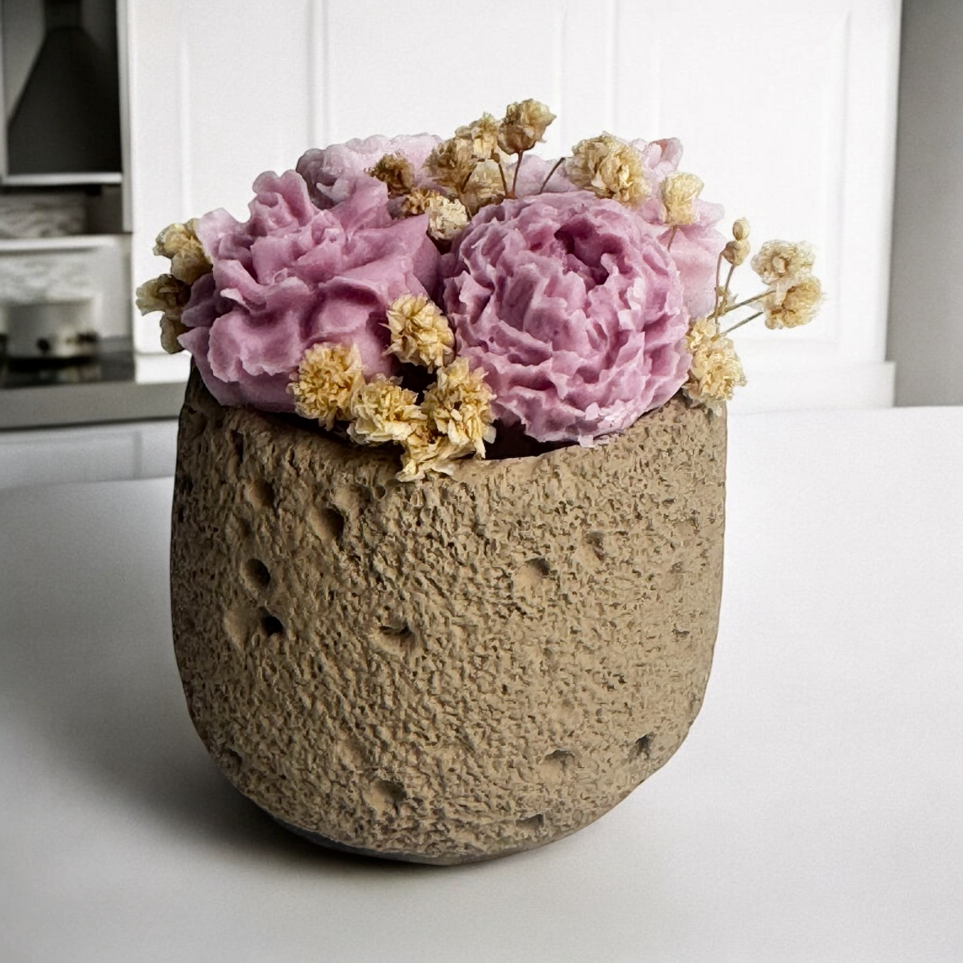 Blooming Candle with blush and lavender wax flowers, textured concrete container, handcrafted decorative piece.