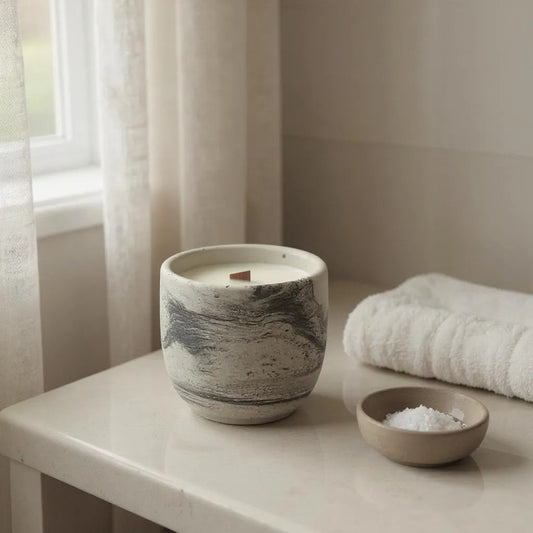 Handmade concrete candle with wooden wick on bathroom counter, minimalist spa decor